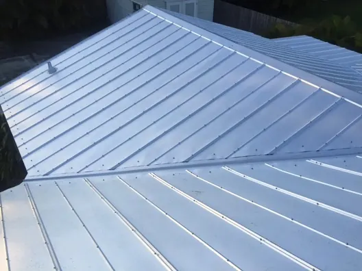 Close view of silver standing-seam metal roof panels meeting at a hip