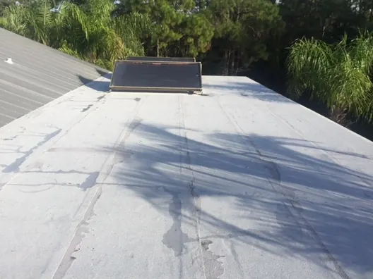 A flat roof with a skylight, showing water staining on the membrane
